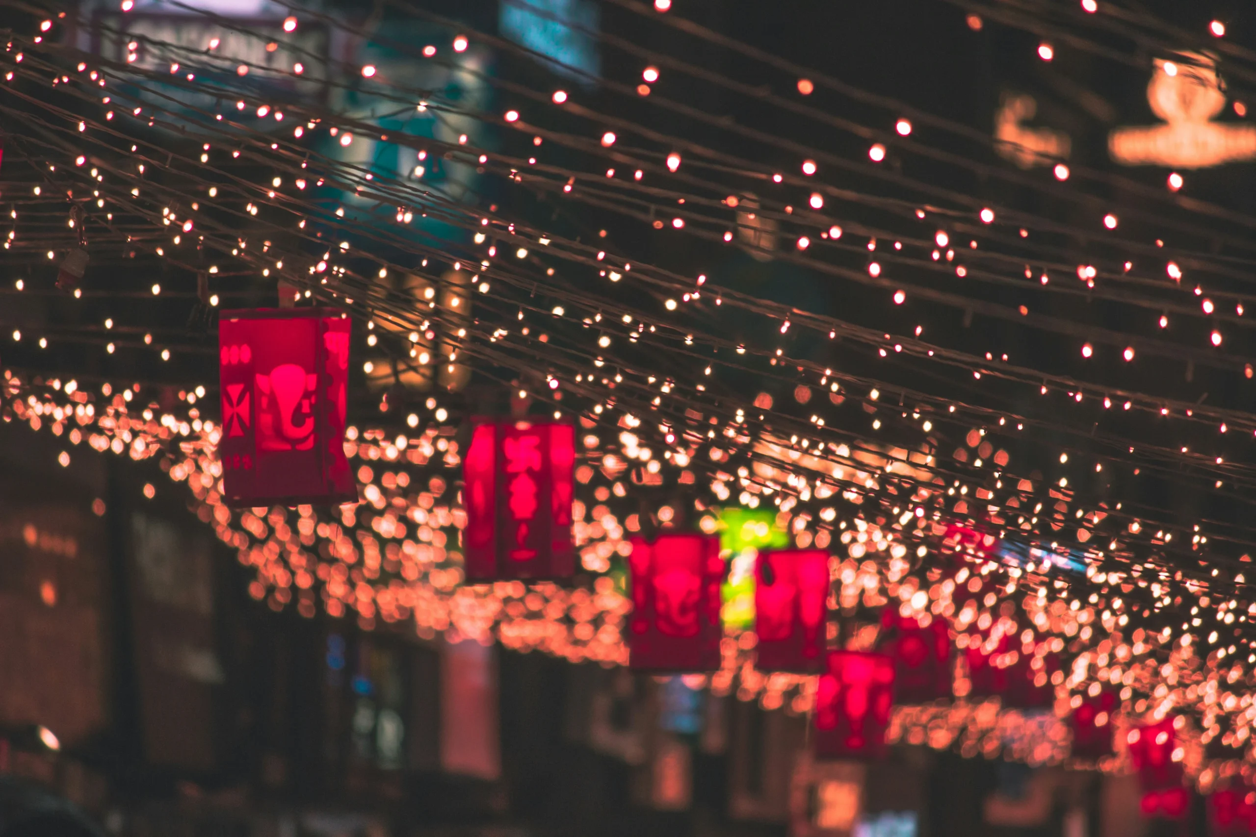 DIwali lights A street adorned with strings of warm, glowing lights and vibrant red lanterns at night, creating a festive and enchanting ambiance.