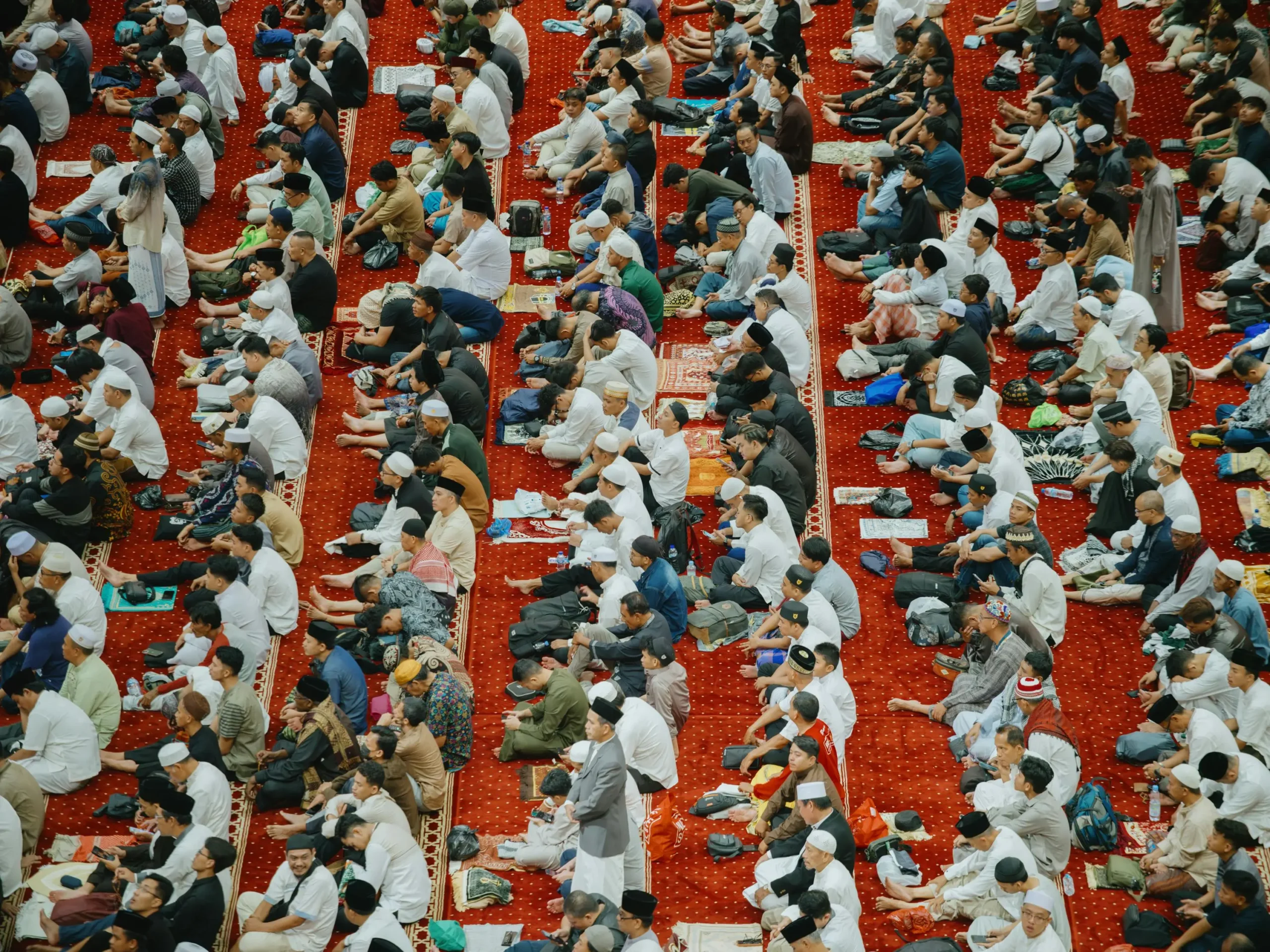 Inside the mosque A large crowd seated on the floor of a mosque, celebrating Eid al-Fitr together in a communal gathering.