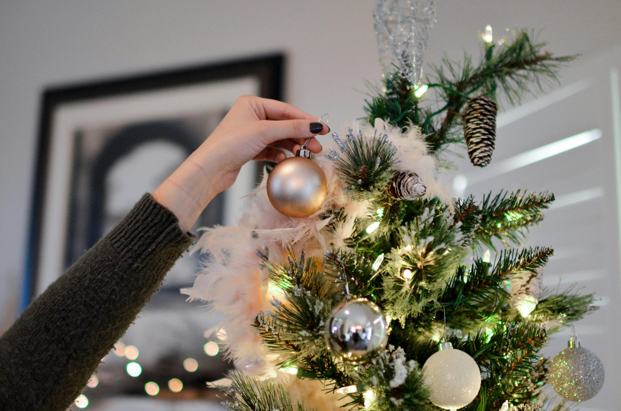 Christmas Tree Decoration An individual decorates a Christmas tree with various ornaments, creating a joyful holiday atmosphere.