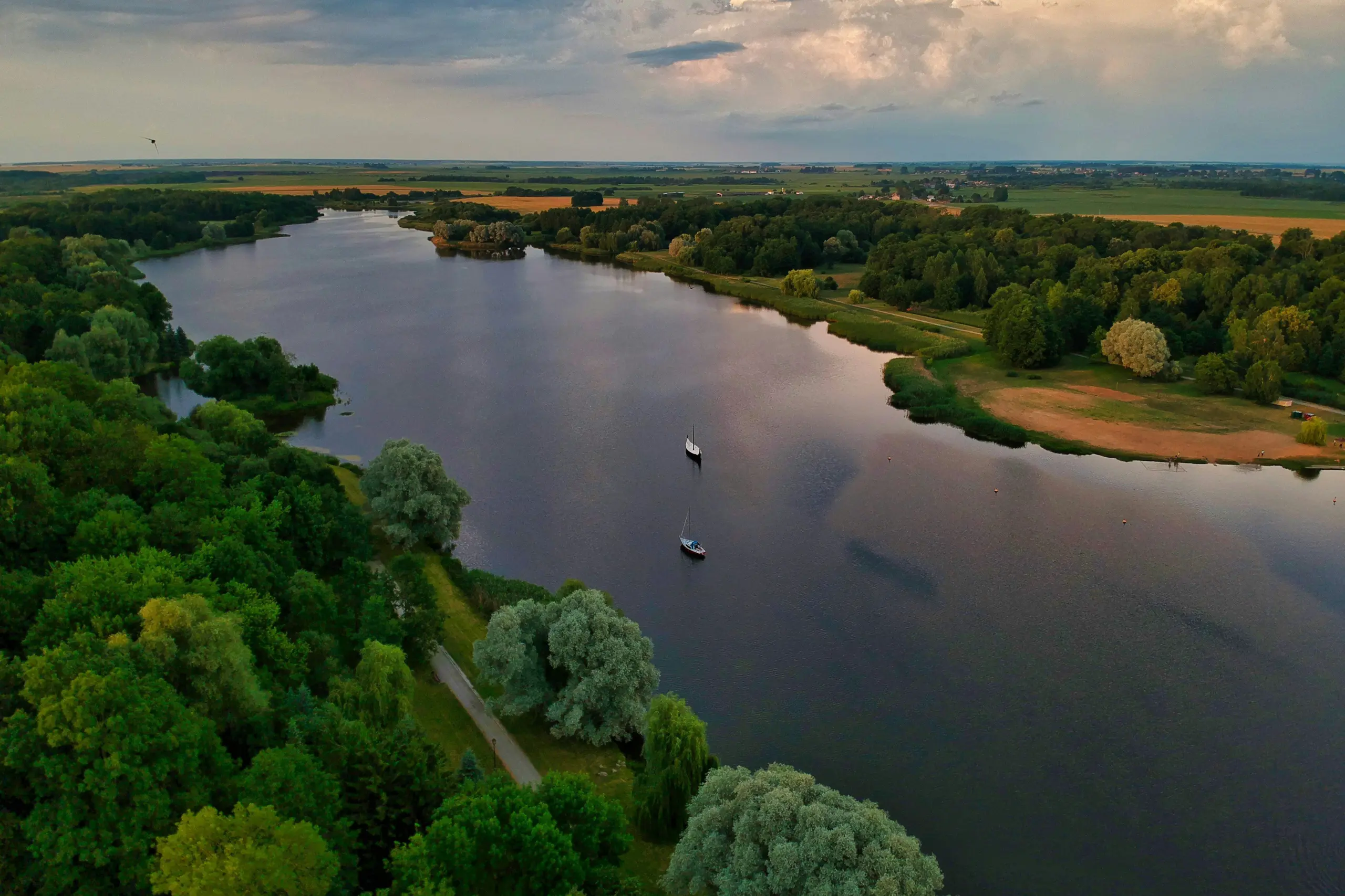 A peaceful lake in Belarus surrounded by green forests and reflecting the blue sky.