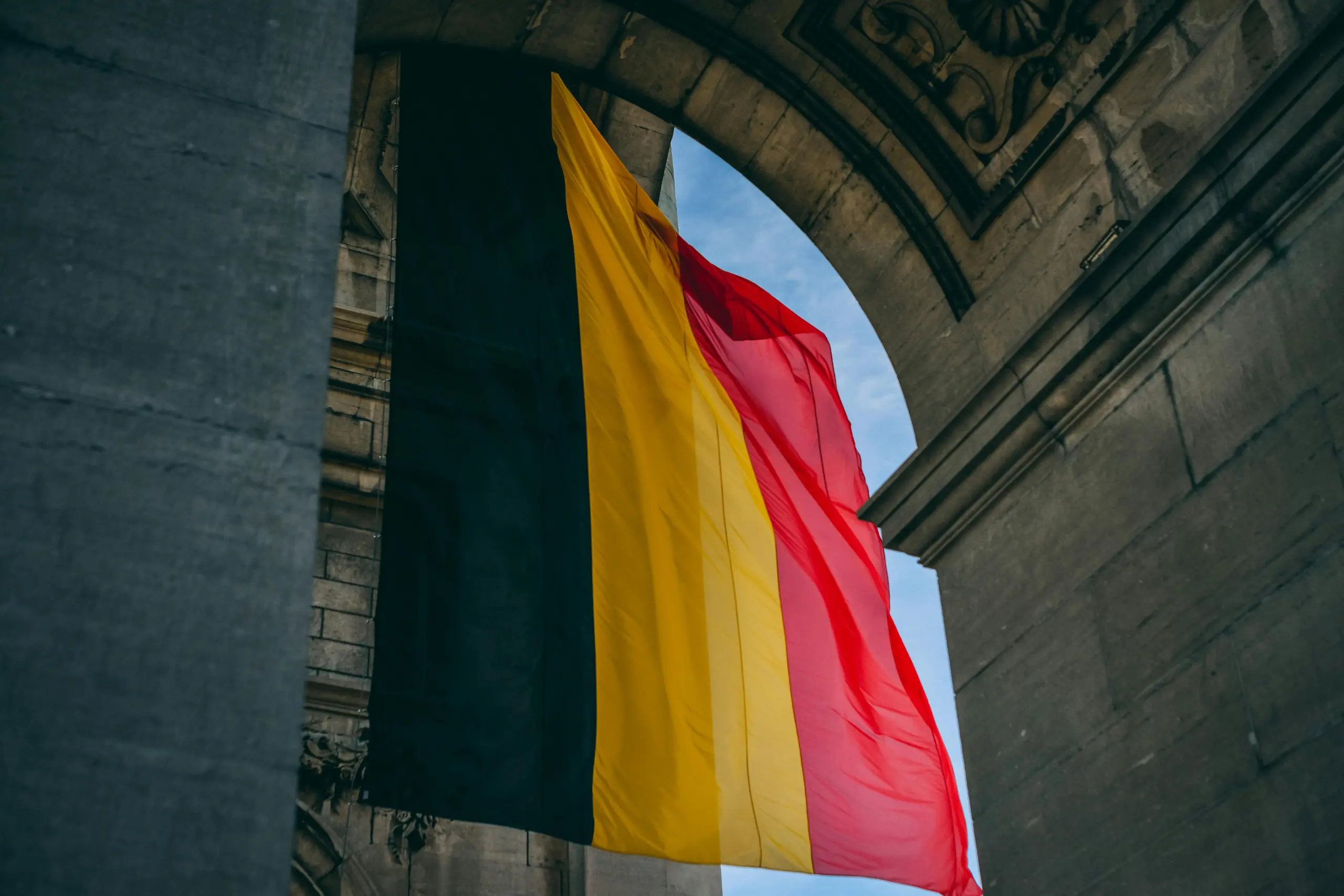 The national flag of Belgium with three vertical stripes of black, yellow, and red waving in the wind.