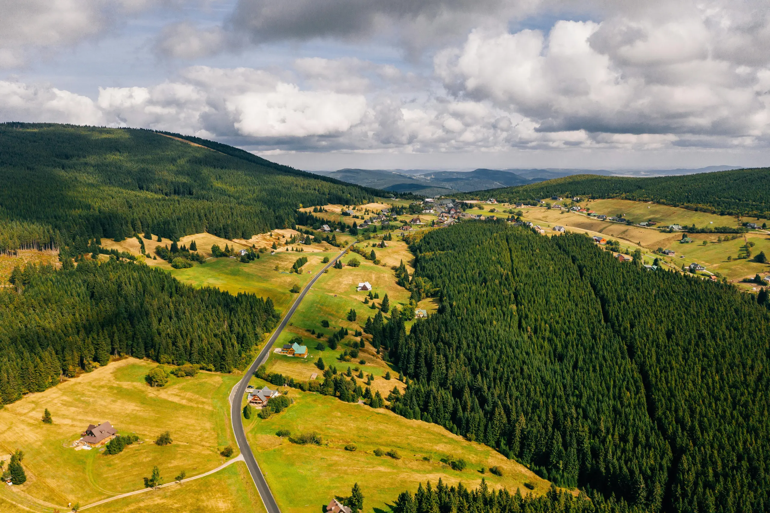 A wide open green landscape in the Czech Republic with a long road running through flat, grassy land.