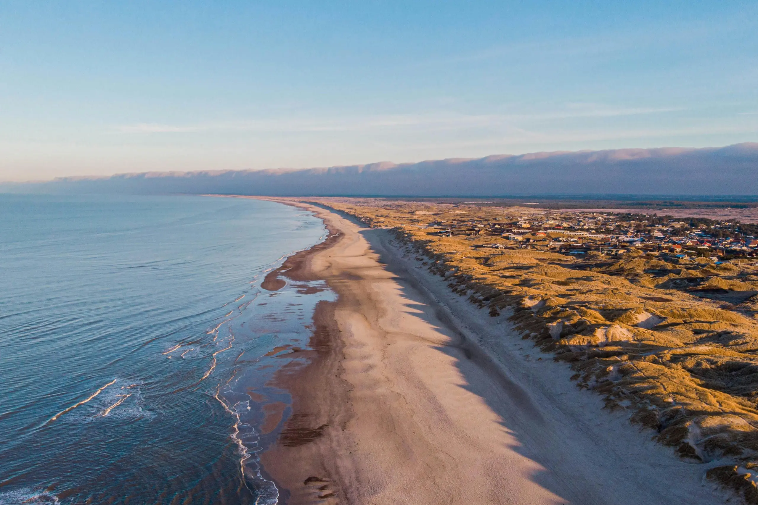 A peaceful Danish beach with soft sand and gentle waves along the shoreline.