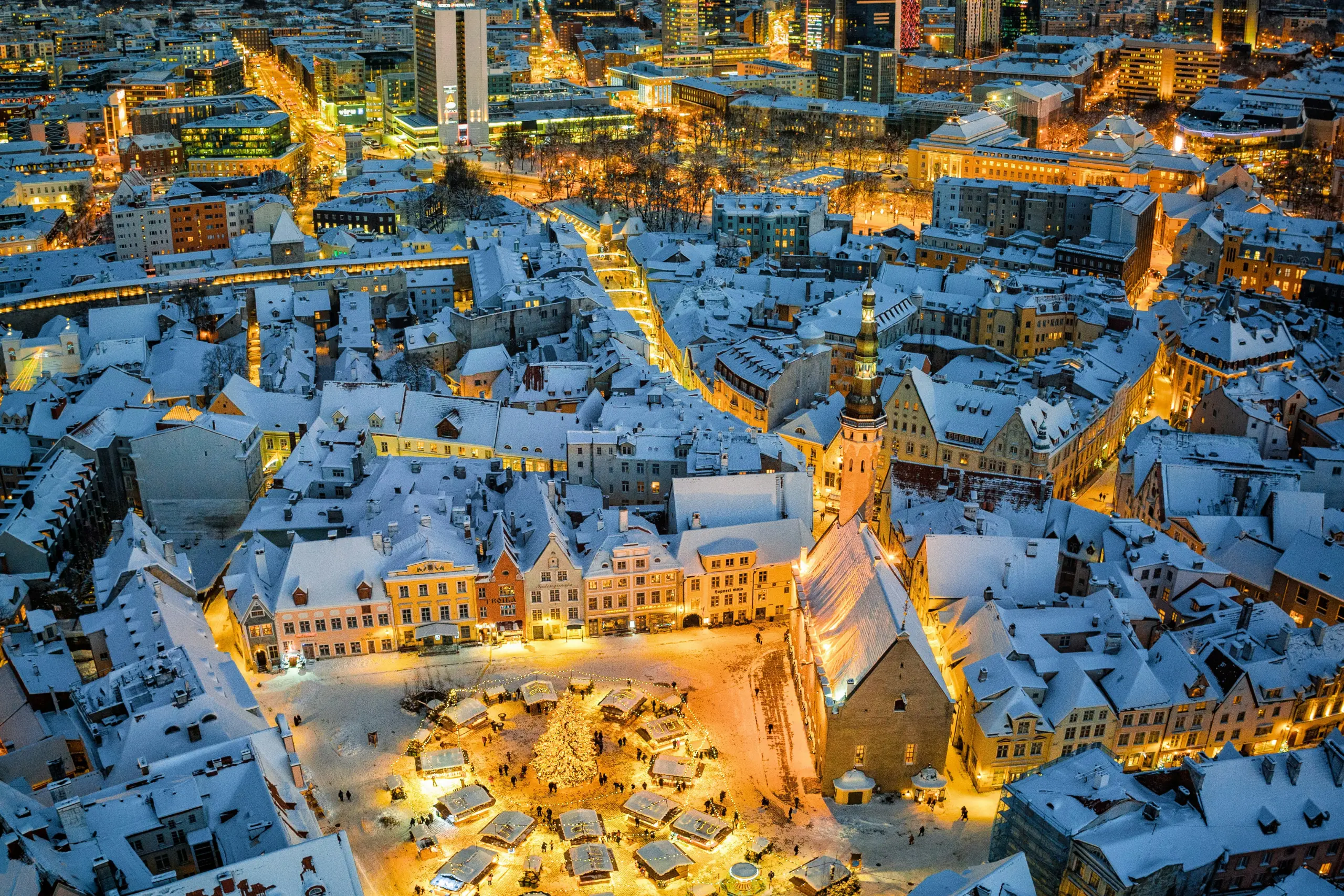 Aerial night view of an Estonian city glowing with twinkling lights and illuminated buildings.